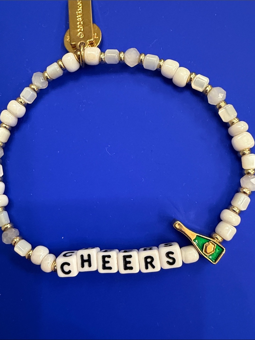 kate spade white beaded "CHEERS" bracelet with gold and green charm